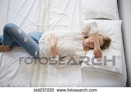 Caucasian woman laying on bed covering eyes View Large Photo Image Stock Image - Caucasian woman laying on bed covering eyes. Fotosearch