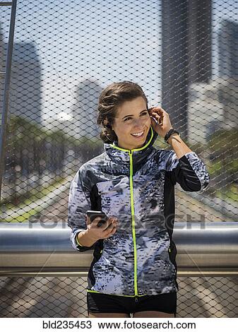Caucasian woman leaning on bridge railing listening to earbuds View Large Photo Image Stock Image - Caucasian woman leaning on bridge railing listening to earbuds. Fotosearch