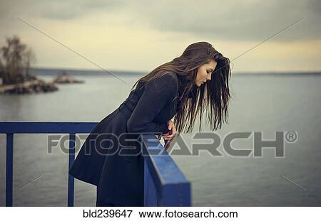Stock Photo - Caucasian woman leaning on railing at waterfront. Fotosearch