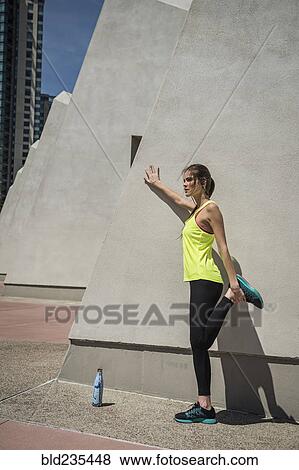 Caucasian woman leaning on wall stretching leg View Large Photo Image Stock Photo - Caucasian woman leaning on wall stretching leg. Fotosearch