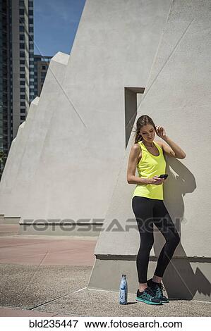 Caucasian woman leaning on wall texting on cell phone View Large Photo Image Stock Photo - Caucasian woman leaning on wall texting on cell phone. Fotosearch