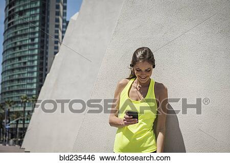 Caucasian woman leaning on wall texting on cell phone View Large Photo Image Stock Photograph - Caucasian woman leaning on wall texting on cell phone. Fotosearch