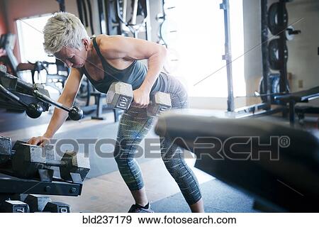 Stock Photo - Caucasian woman lifting barbell in gymnasium. Fotosearch