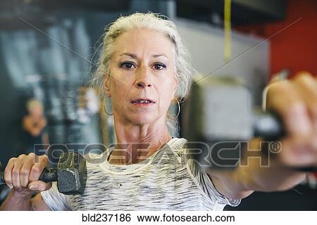Caucasian woman lifting dumbbells in gymnasium View Large Photo Image Stock Photograph - Caucasian woman lifting dumbbells in gymnasium. Fotosearch