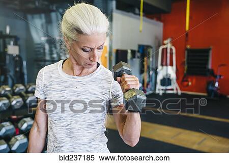 Stock Photography - Caucasian woman lifting dumbbells in gymnasium. Fotosearch