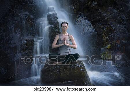 Caucasian woman meditating on rock near waterfall View Large Photo Image Stock Photo - Caucasian woman meditating on rock near waterfall. Fotosearch
