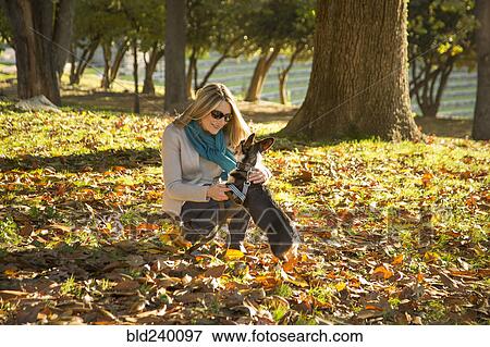 Stock Photo - Caucasian woman petting dog in park. Fotosearch