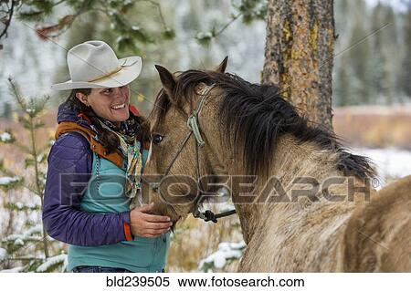 Stock Photography - Caucasian woman petting horse in winter. Fotosearch