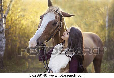 Stock Photograph - Caucasian woman petting horse. Fotosearch