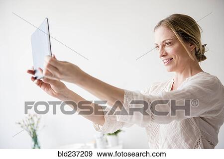 Stock Photo - Caucasian woman posing for selfie using digital tablet. Fotosearch