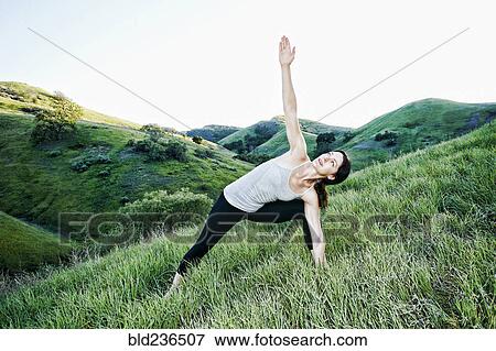 Stock Photo - Caucasian woman practicing yoga on hill. Fotosearch