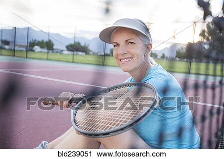 Stock Image - Caucasian woman resting and holding tennis racket. Fotosearch