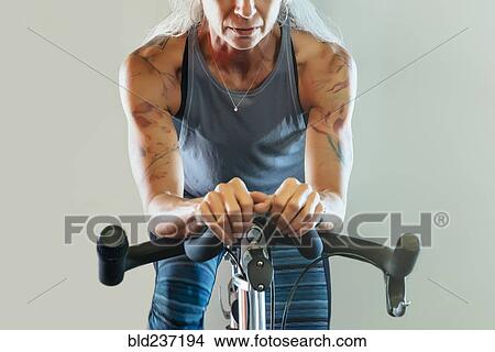 Picture - Caucasian woman riding stationary bicycle. Fotosearch