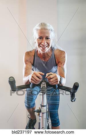 Stock Photo - Caucasian woman riding stationary bicycle. Fotosearch