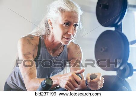 Stock Photo - Caucasian woman riding stationary bicycle. Fotosearch