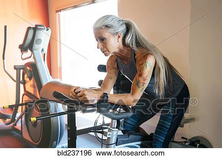 Caucasian woman riding stationary bicycle in gymnasium View Large Photo Image Stock Photograph - Caucasian woman riding stationary bicycle in gymnasium. Fotosearch