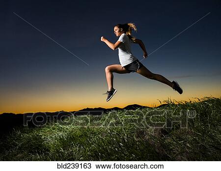 Stock Image - Caucasian woman running at sunset. Fotosearch