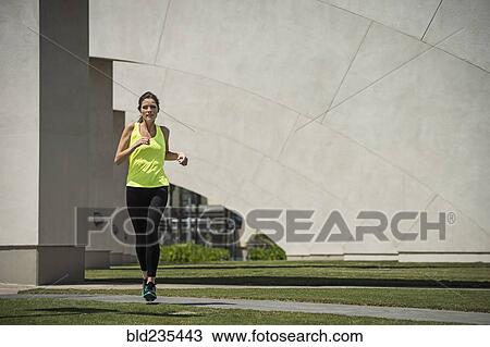 Stock Image - Caucasian woman running near pillars. Fotosearch