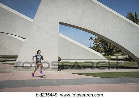 Stock Photo - Caucasian woman running near architecture. Fotosearch