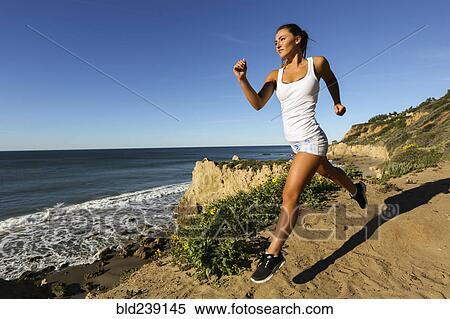 Stock Photography - Caucasian woman running on beach. Fotosearch