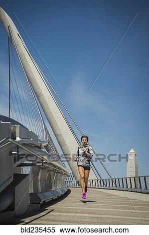 Stock Photography - Caucasian woman running on bridge. Fotosearch