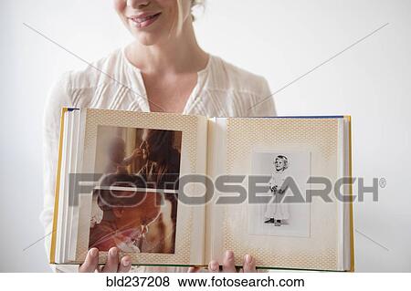 Stock Photo - Caucasian woman showing photo album. Fotosearch