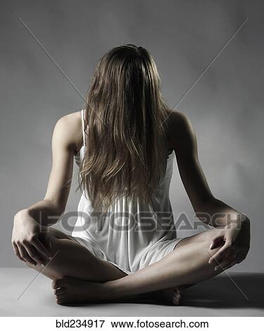 Stock Photo - Caucasian woman sitting cross-legged with hair covering face. Fotosearch