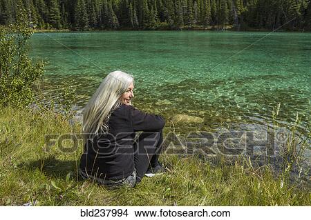 Caucasian woman sitting near river View Large Photo Image Picture - Caucasian woman sitting near river. Fotosearch