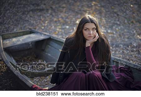 Stock Image - Caucasian woman sitting on boat on land. Fotosearch