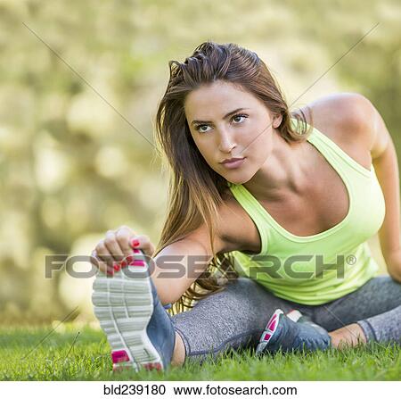 Caucasian woman sitting on grass stretching leg View Large Photo Image Stock Image - Caucasian woman sitting on grass stretching leg. Fotosearch