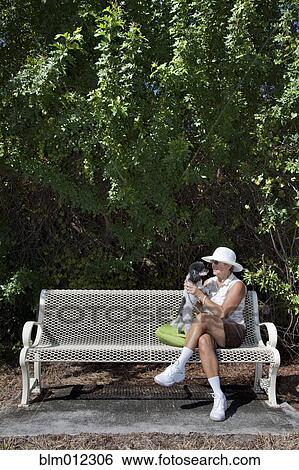 Caucasian woman sitting on park bench with dog View Large Photo Image Stock Photograph - Caucasian woman sitting on park bench with dog. Fotosearch