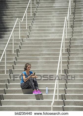 Caucasian woman sitting on staircase texting on cell phone View Large Photo Image Stock Image - Caucasian woman sitting on staircase texting on cell phone. Fotosearch