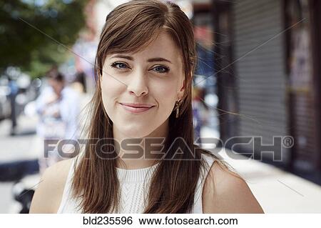 Stock Photograph - Caucasian woman smiling on city sidewalk. Fotosearch