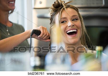 Stock Image - Caucasian woman smiling with hair stylist. Fotosearch