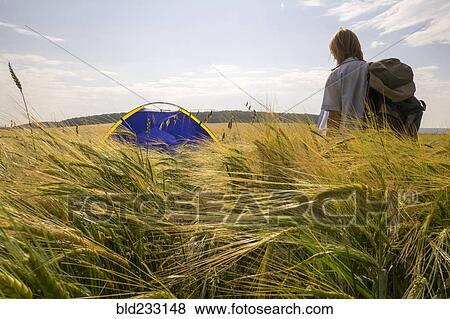 Stock Photo - Caucasian woman standing in field near camping tent. Fotosearch