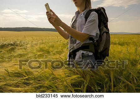 Stock Photography - Caucasian woman standing in field using cell phone. Fotosearch