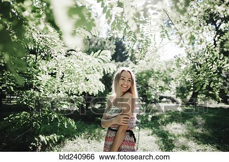 Caucasian woman standing near green trees View Large Photo Image Stock Photograph - Caucasian woman standing near green trees. Fotosearch