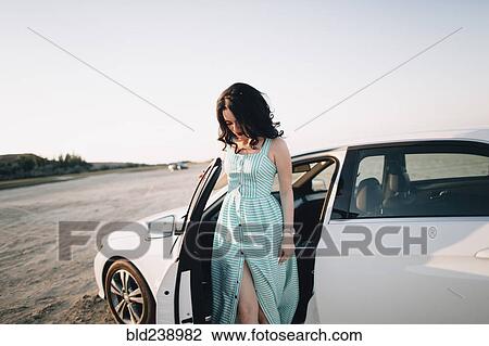 Stock Image - Caucasian woman standing near open car door. Fotosearch