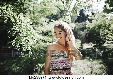 Stock Image - Caucasian woman standing near trees. Fotosearch
