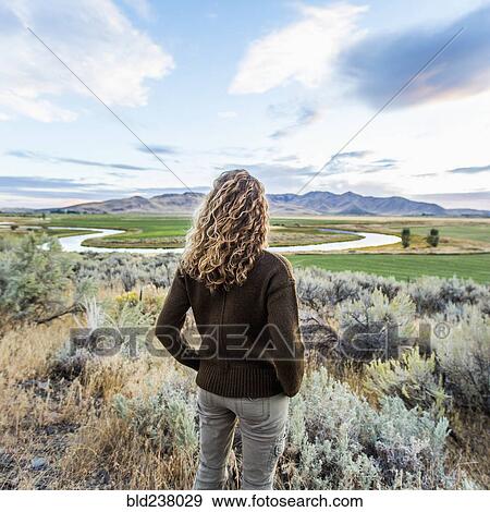Caucasian woman standing near winding river View Large Photo Image Stock Photo - Caucasian woman standing near winding river. Fotosearch