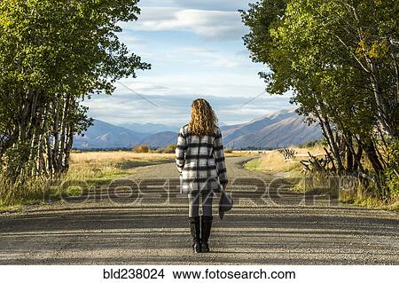 Picture - Caucasian woman standing on dirt road. Fotosearch