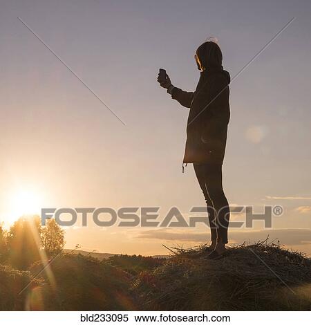 Caucasian woman standing on hay holding cell phone View Large Photo Image Stock Photography - Caucasian woman standing on hay holding cell phone. Fotosearch