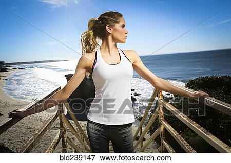 Stock Photo - Caucasian woman standing on staircase at beach. Fotosearch