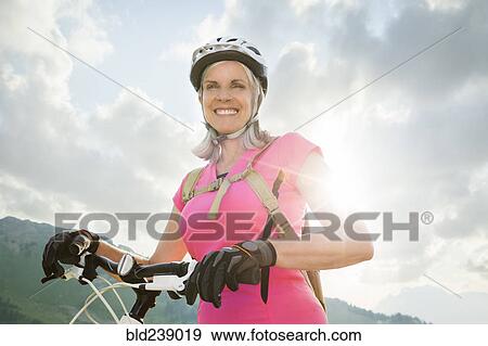 Stock Photo - Caucasian woman standing with mountain bike. Fotosearch