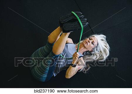 Stock Image - Caucasian woman stretching leg with resistance band . Fotosearch