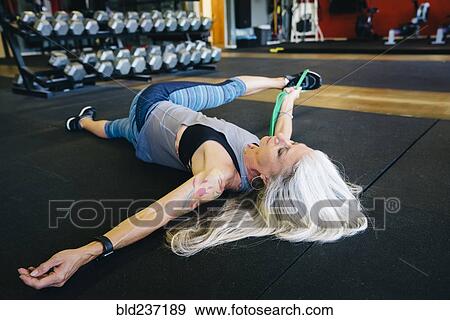 Stock Photo - Caucasian woman stretching leg with resistance band. Fotosearch