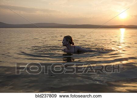 Caucasian woman swimming in lake at sunset View Large Photo Image Stock Photo - Caucasian woman swimming in lake at sunset. Fotosearch