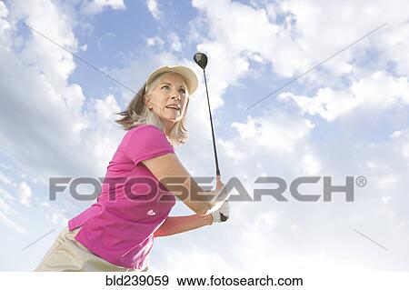 Stock Photo - Caucasian woman swinging golf club. Fotosearch