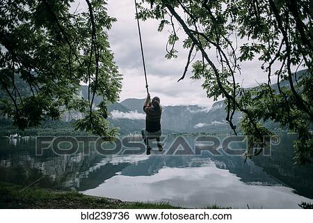 Caucasian woman swinging on rope swing at lake View Large Photo Image Stock Photograph - Caucasian woman swinging on rope swing at lake. Fotosearch
