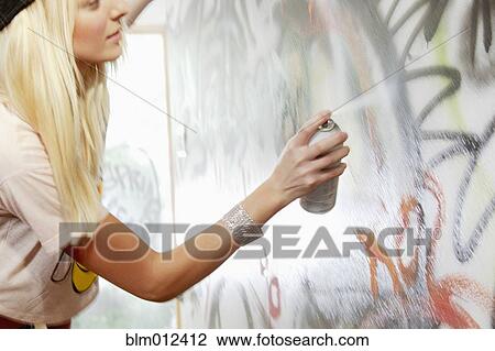 Stock Image - Caucasian woman tagging wall with graffiti. Fotosearch
